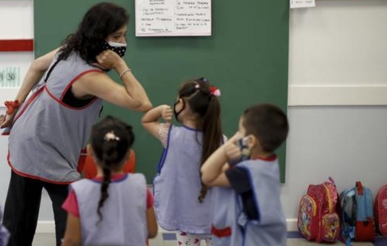 Una maestra, en Buenos Aires, enseña a sus alumnos de cinco años a saludar con un codazo durante el regreso a las aulas en medio de la pandemia. Foto Ap / archivo
